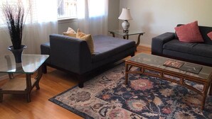 A living room with a dark grey sofa, a glass coffee table, and a patterned rug. - Charming Cupertino Retreat: Spacious Home near Apple HQ, Dining and Shopping! (Cupertino)