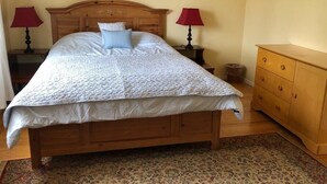 A neatly made bed with a wooden headboard, two bedside lamps, a wooden dresser, and a patterned rug. - Charming Cupertino Retreat: Spacious Home near Apple HQ, Dining and Shopping! (Cupertino)