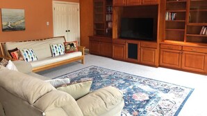 A living room with a sofa, a television, wooden cabinets, and a ceiling fan. - Charming Cupertino Retreat: Spacious Home near Apple HQ, Dining and Shopping! (Cupertino)