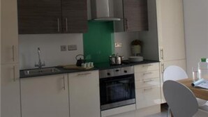 A modern kitchen with a stove, oven, and sink. There is a dining table with chairs. - Beautiful 2-bed Apartment in Southend-on-sea (Southend-on-Sea)