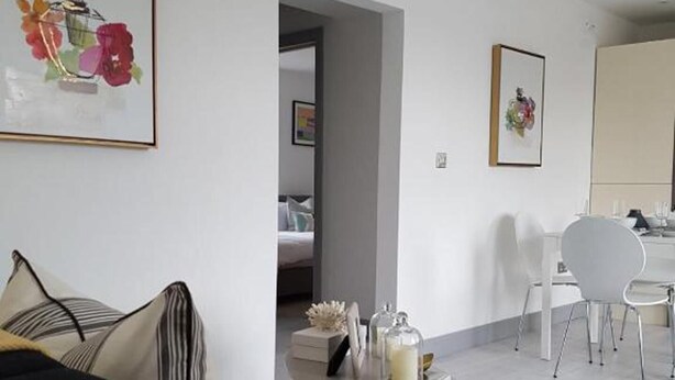 A modern living room with a sofa, a dining area with a table and chairs, and a hallway leading to another room. - Beautiful 2-bed Apartment in Southend-on-sea (Southend-on-Sea)