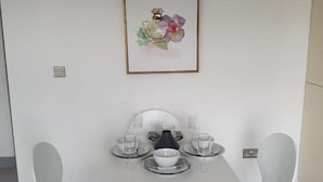 A modern dining area with a white table, two chairs, and a framed artwork on the wall. - Beautiful 2-bed Apartment in Southend-on-sea (Southend-on-Sea)