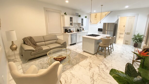 A modern living room with a sofa, a coffee table, and a dining area with chairs. - Hidden Gem in plain sight! Adorable 3 Bdrm Duplex near Hospitals & Universities. (Cincinnati)