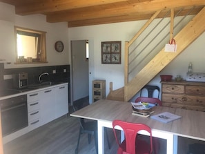 A kitchen with modern appliances, a dining area with a wooden table and chairs, and a staircase leading to another level. - Parking space, TV, 66 m², Arêches-Beaufort (Beaufort)