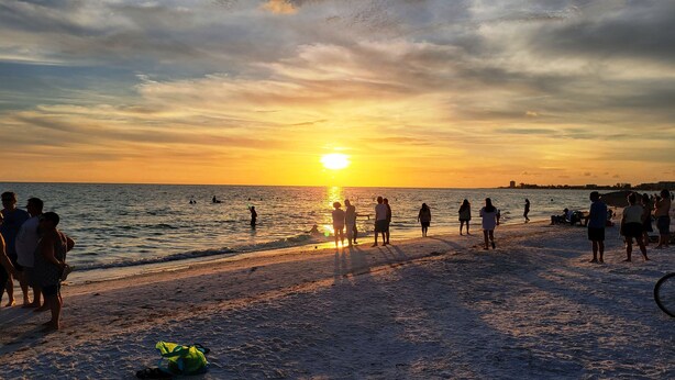A beach scene with people walking along the shore during sunset. - Lovely 2 bedroom luxury villa with a pool, Beach is 2 miles away. (Sarasota)