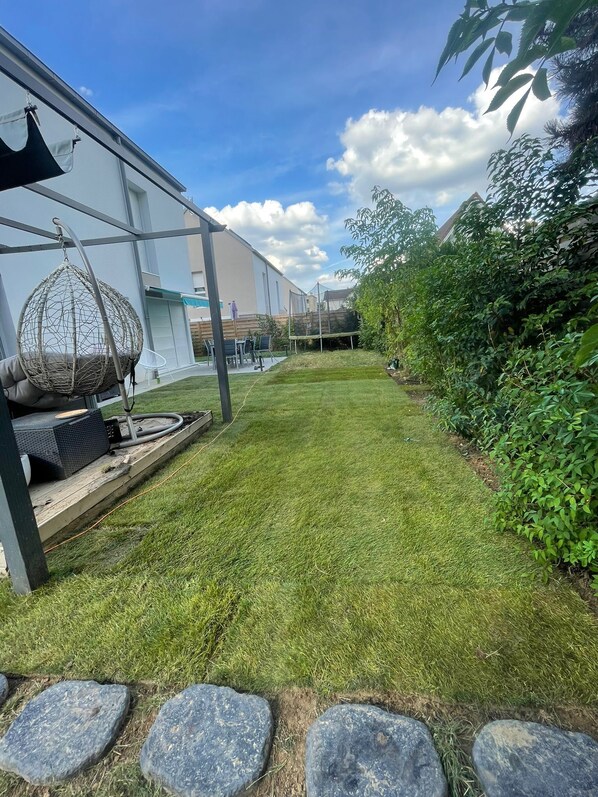 A well-maintained backyard with a hanging chair, a trampoline, and a small table with speakers. - Luxury suite with a private outdoor spa (Épinay-sur-Seine)