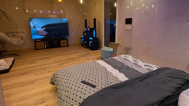 Een moderne slaapkamer met een groot bed, een televisie en een spelconsole.