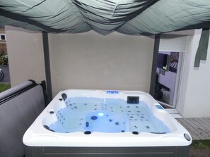 Relax in the outdoor hot tub under a shaded canopy.