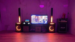 Een thuisbioscoopopstelling met een televisie, twee Marshall speakers en een subwoofer.