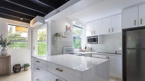A modern kitchen with white cabinetry, a stainless steel refrigerator, and a built-in microwave. - Beachside 2-Bed House with Pool, Courtyard & BBQ (Sunshine Beach)