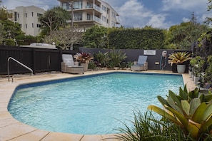A swimming pool with lounge chairs, a fenced area, and a sign prohibiting jumping into the pool. - Beachside 2-Bed House with Pool, Courtyard & BBQ (Sunshine Beach)