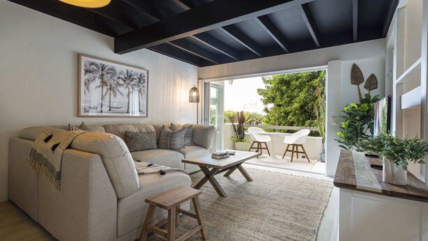 A living room with a sofa, coffee table, and a view of the outdoors. - Beachside 2-Bed House with Pool, Courtyard & BBQ (Sunshine Beach)
