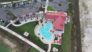 Eine Vogelperspektive zeigt ein Resort mit Pool, einem Gebäude mit rotem Dach und einem Parkplatz.