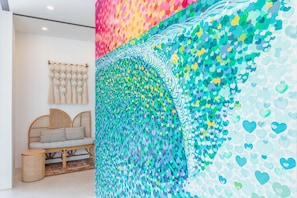 Relax in a stylish space with a vibrant art piece, wicker sofa, and woven rug.
