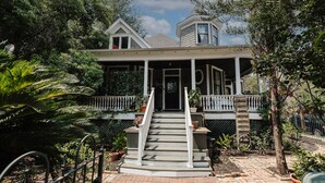 A two-story house with a porch, a small tower-like structure on the roof, and a staircase leading to the entrance. - Historical Houston - 2 king beds - vintage boho - centrally located (Houston)