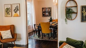 A dining area with a table set for four, a yellow chair, and a chandelier. - Historical Houston - 2 king beds - vintage boho - centrally located (Houston)