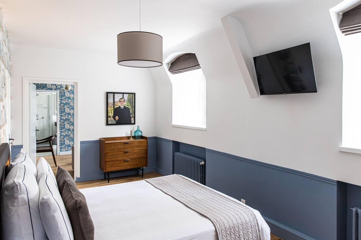 Une chambre à coucher avec un lit, une commode et un téléviseur fixé au mur.