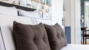 A bed with a white headboard and dark brown pillows, set against a wall with a blue and white patterned wallpaper. - La Castagnère de Bergory (Wervicq-Sud)