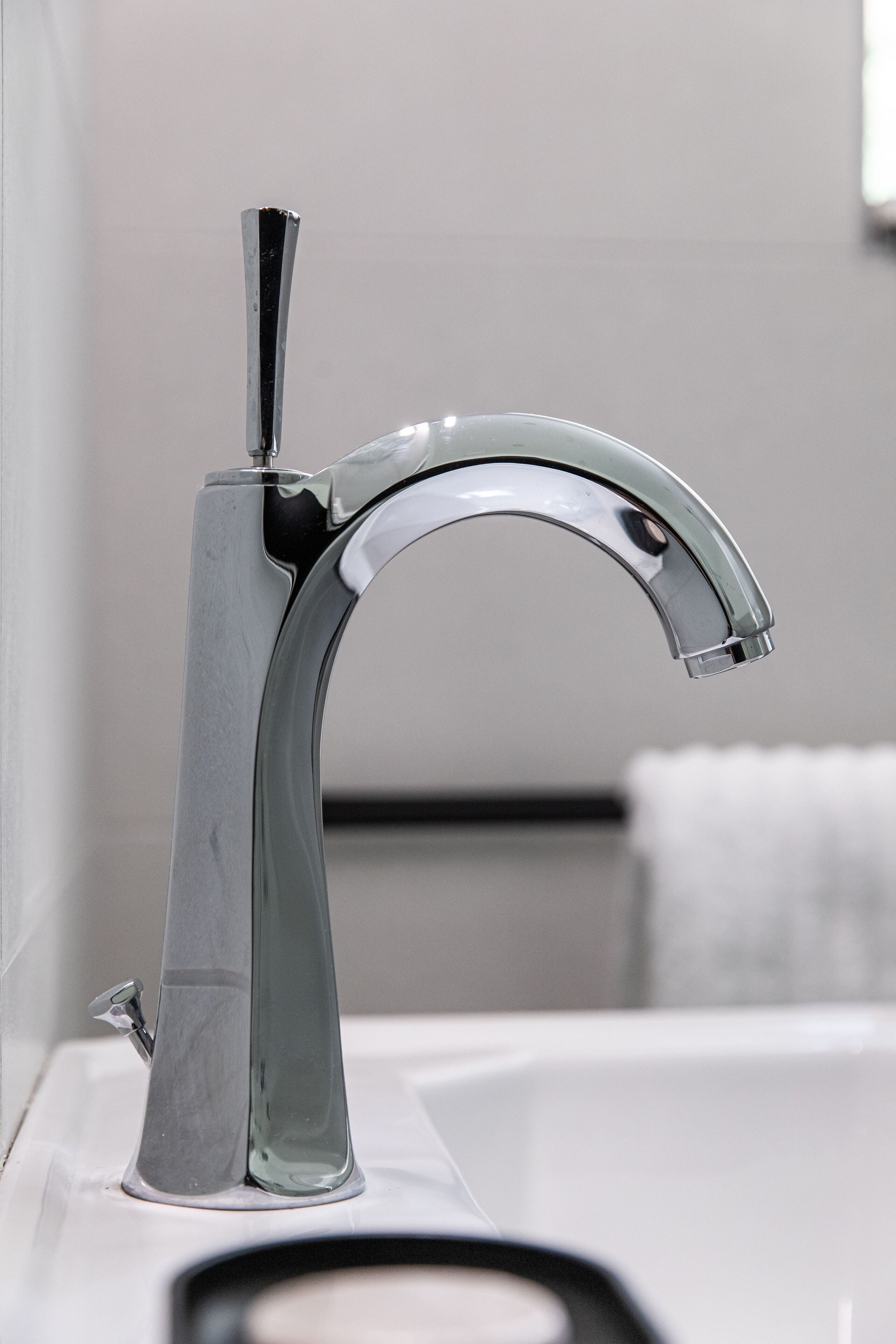 A modern bathroom with a chrome faucet and a white sink.