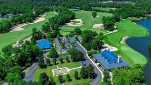 An aerial view of a golf course with a clubhouse, parking area, and a lake. - Amazing 3BD 1st Floor Pawleys Island at True Blue Resort Golf 4 Pools Near Beach (Pawleys Island)