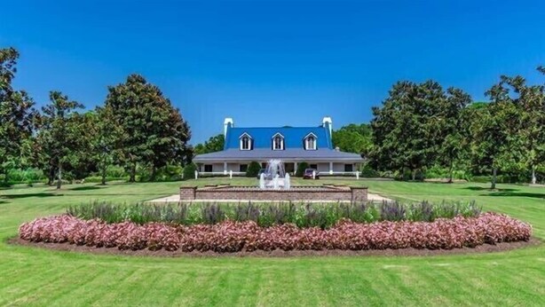 A large, stately building with a symmetrical facade, a central fountain, and a well-manicured lawn with a flower bed in the foreground. - Amazing 3BD 1st Floor Pawleys Island at True Blue Resort Golf 4 Pools Near Beach (Pawleys Island)