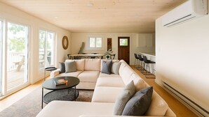 Un salón amplio con un sofá seccional en forma de L, una mesita de centro redonda y un comedor con mesa y sillas.