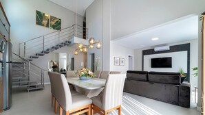 Een moderne woonruimte met een eethoek, een trap, een bank en een televisie.