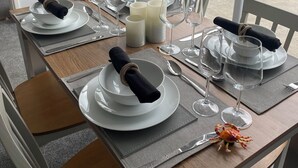 Una tavola da pranzo imbandita per quattro, con piatti bianchi, tovaglioli neri e bicchieri da vino.