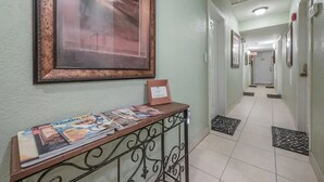A hallway with a framed picture on the wall, a small table with magazines, and a tiled floor. - Comfy & Cozy Ybor City Studio steps from 7th Ave. #5 (Tampa)