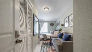 A compact living space with a sofa, a bed, and a patterned rug. - Comfy & Cozy Ybor City Studio steps from 7th Ave. #5 (Tampa)