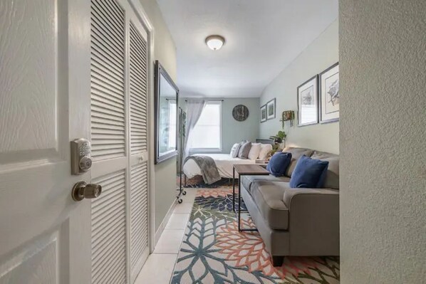 A compact living space with a sofa, a bed, and a patterned rug.