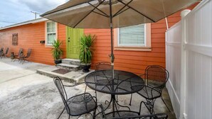 A patio with a round metal table and four chairs, a large umbrella, and two potted plants. - Comfy & Cozy Ybor City Studio steps from 7th Ave. #5 (Tampa)