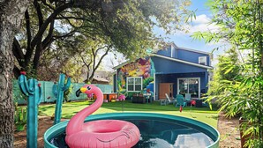 A backyard with a swimming pool, a mural on the house, and a flamingo float. - Chic 4BR Austin Retreat w/ Cowboy Pool, Hot Tub & Sauna — Near Downtown (Austin)