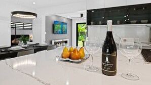 A modern kitchen with a marble countertop, a bottle of wine, and a plate of pears. - 3 Bedroom Luxury Modern Home with Heated Pool and Near Downtown Dining & Shops! (Wilton Manors)