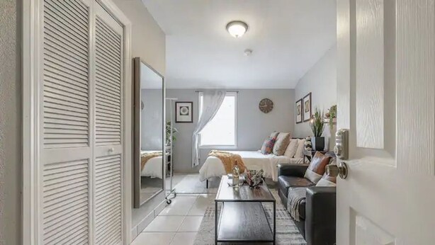 Een moderne woonkamer met een bank, salontafel en een grote spiegel.