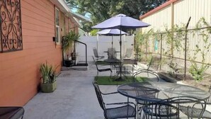Un patio con mobiliario exterior y una sombrilla.