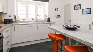 Una cocina moderna con armarios blancos, un ventanal grande, un lavamanos y un tazón colorido sobre la encimera.