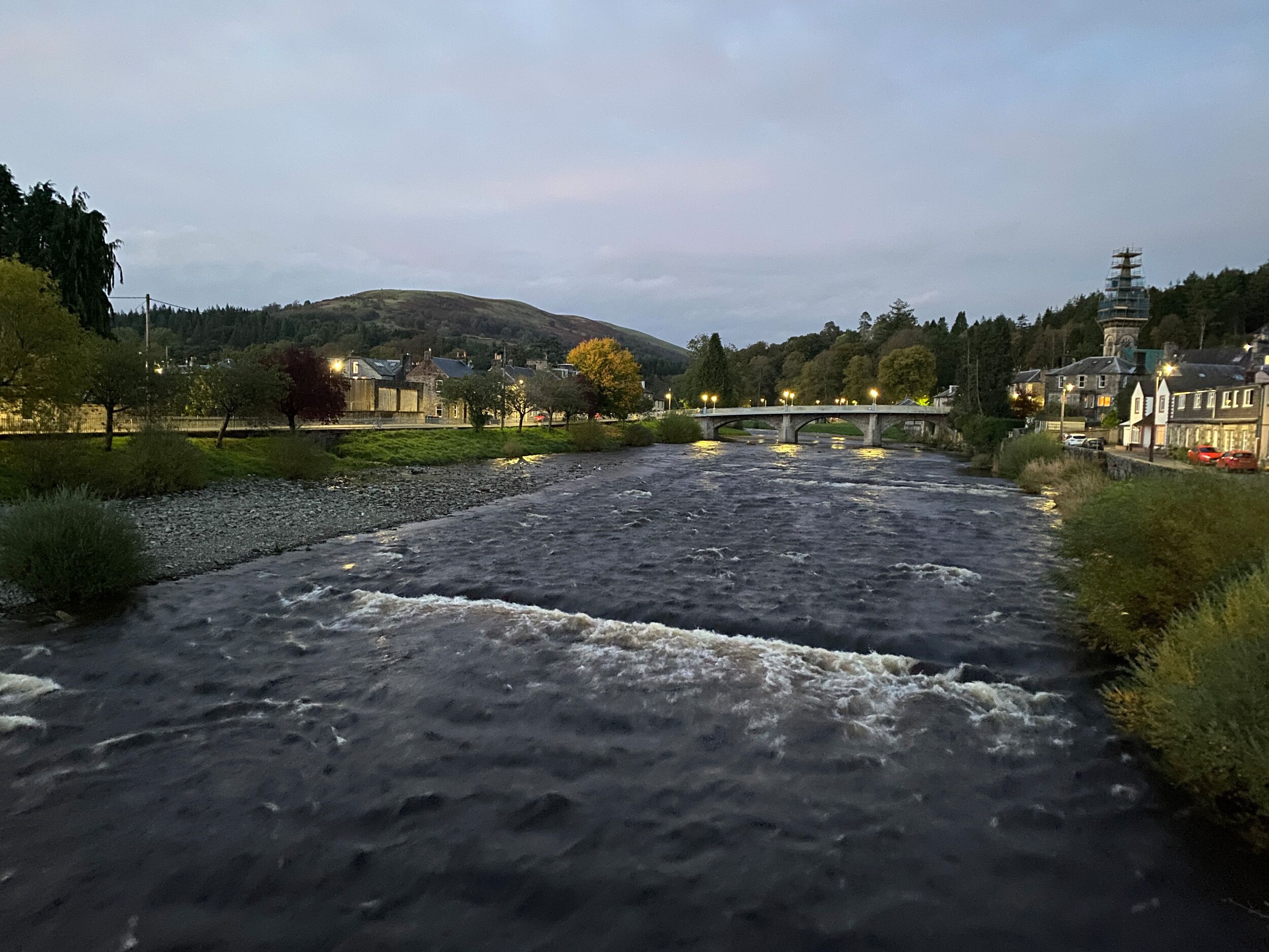 A river flowing under a bridge with buildings on the banks.