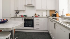 Una cocina moderna con armarios blancos, horno empotrado, campana de acero inoxidable y encimera de granito.