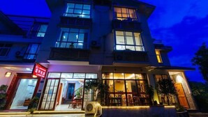 A multi-story hotel with large windows and a well-lit entrance. - Mingxuan Inn (Wuyishan)
