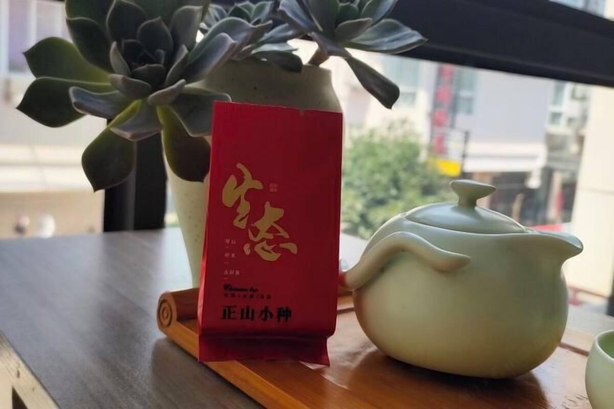 A table with a potted plant, a teapot, and a red packet with Chinese characters.