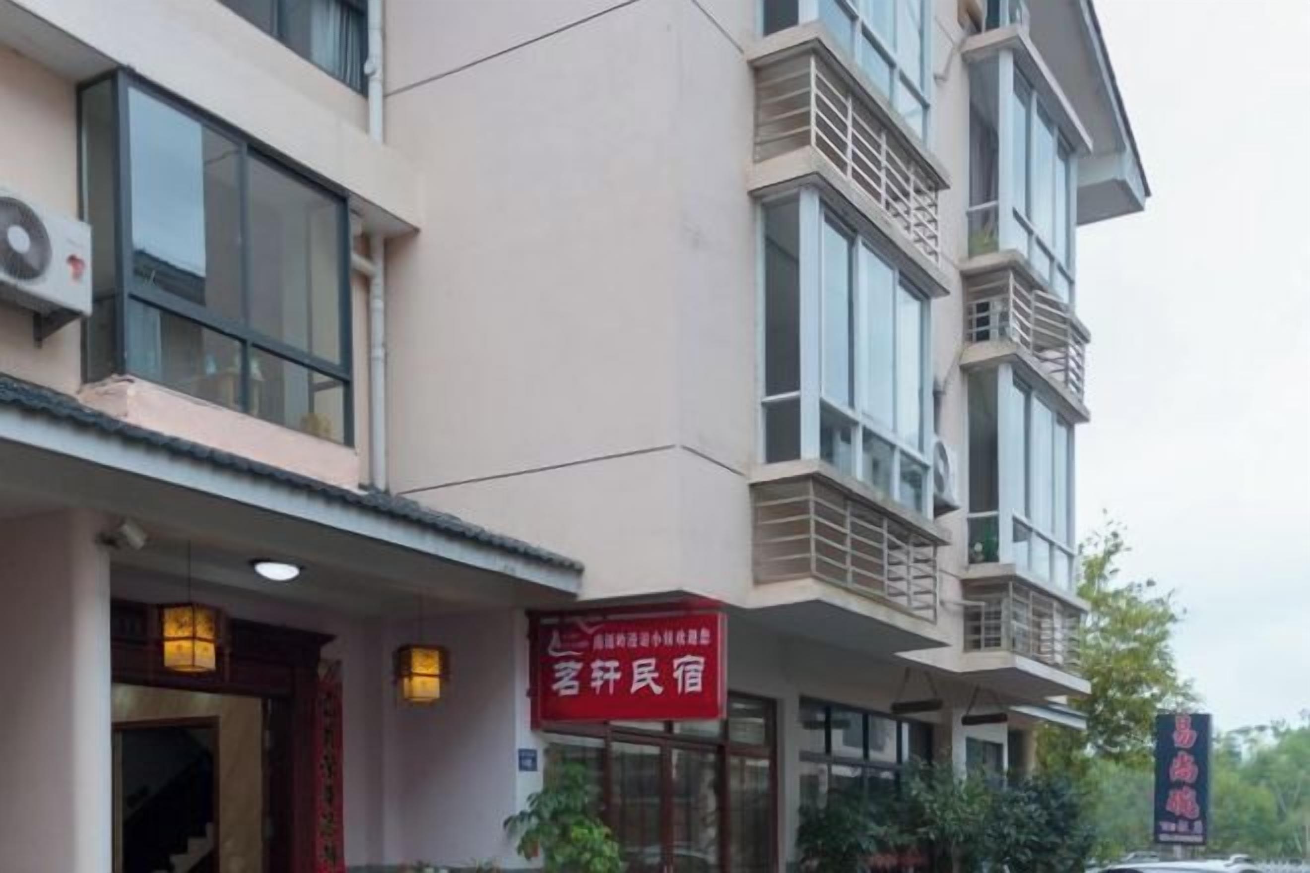 A multi-story building with a red sign indicating a guesthouse.