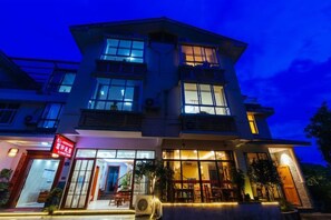 A multi-story hotel with a prominent entrance, large windows, and outdoor seating area. - Mingxuan Inn (Wuyishan)