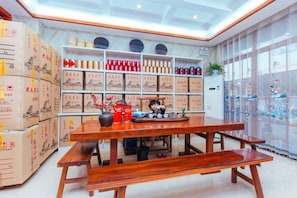 Una habitación con una mesa de madera y bancos, estantes con cajas y utensilios de cocina, y un ventanal con vistas.