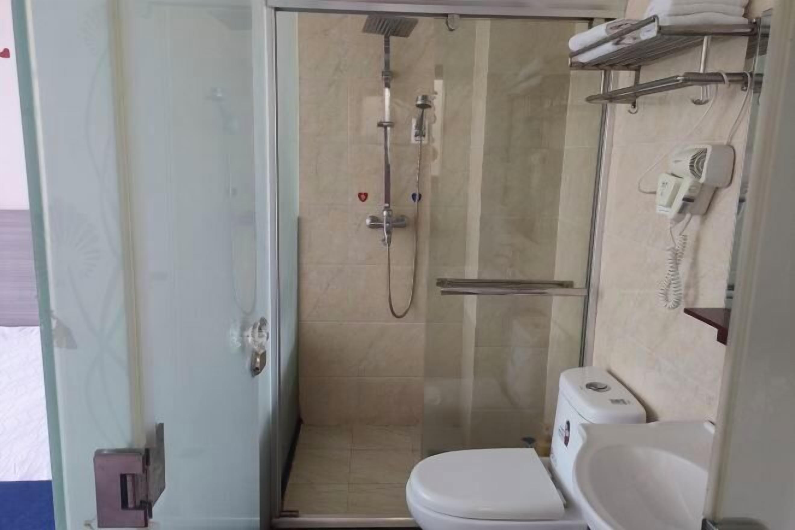 Une petite salle de bain avec une douche à parois de verre, des toilettes et un lavabo.