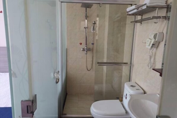 A small bathroom with a glass shower enclosure, a toilet, and a sink. - Mingxuan Inn (Wuyishan)