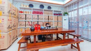 A room with a wooden dining table, benches, and shelves with boxes and containers. - Mingxuan Inn (Wuyishan)
