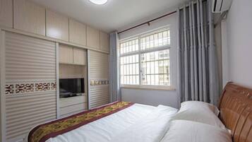 A bedroom with a bed, wardrobe, and a window with curtains.