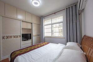 A bedroom with a bed, wardrobe, and a window with curtains. - Mingxuan Inn (Wuyishan)