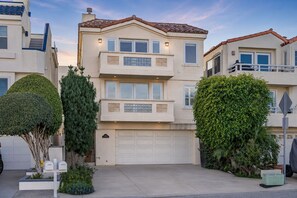 A multi-story residential building with a garage, a balcony, and well-maintained landscaping.